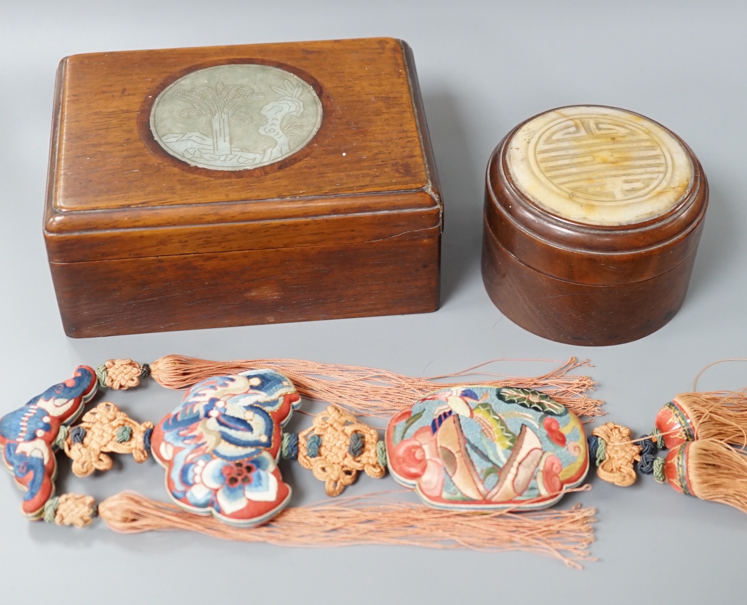 Two 19th century Chinese hardstone inset hardwood boxes and an embroidered amulet charm, largest box 12.5cm